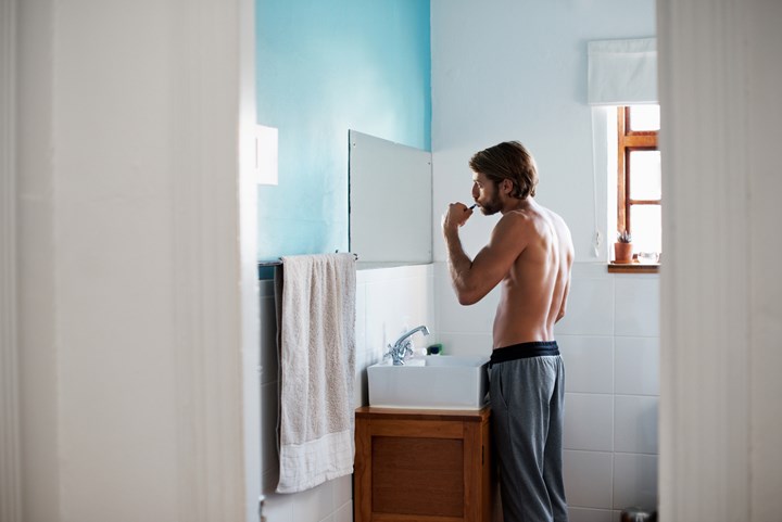 Man brushing teeth in bathroom.